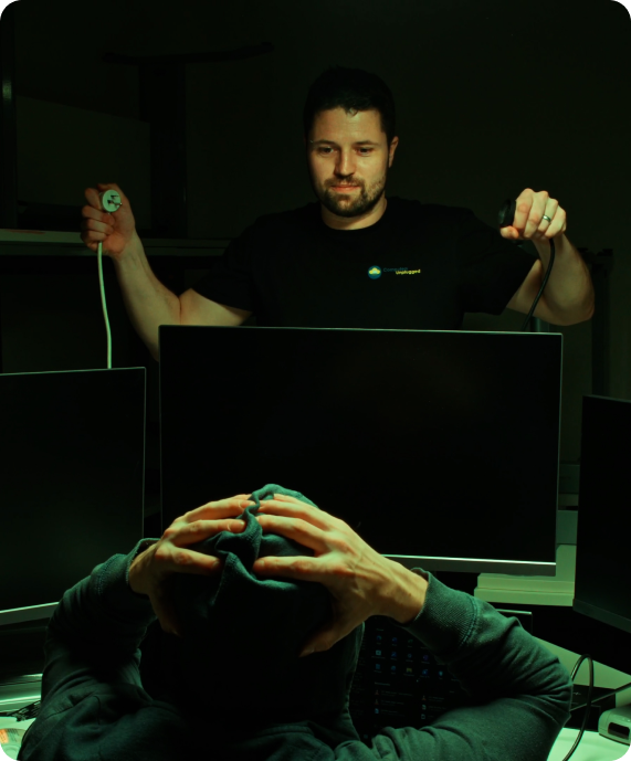Cybersecurity Solutions for Businesses A technician prepares to connect a monitor while a person looks stressed.