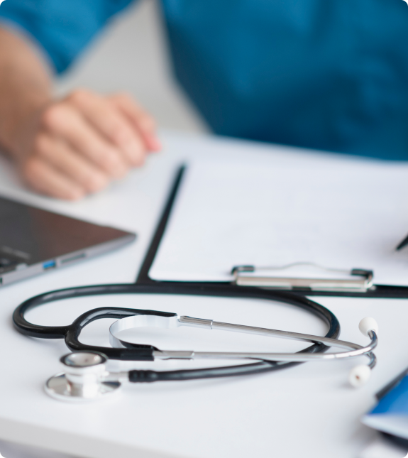 Stethoscope on Desk A stethoscope resting on a desk with a laptop and clipboard.